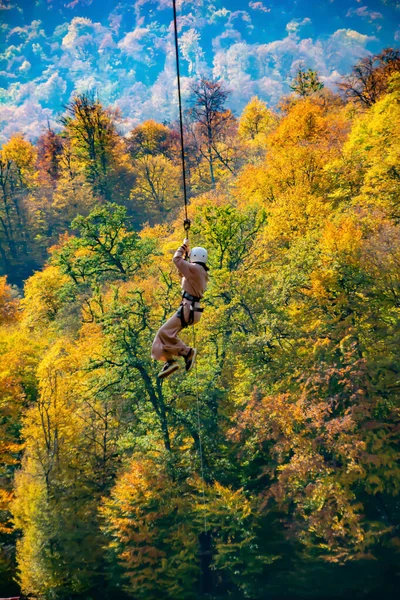 森の中の湖の上にジップライン 秋の森の背景にジップラインに若い男 写真の秋の森 ジップライン — ストック写真