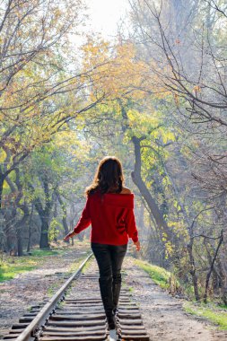 Kadın, demiryolu ve peri ormanı. Güzel bir kadın sonbahar ormanında demiryolunda yürüyor.