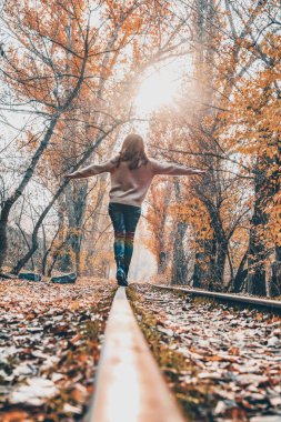 Kadın, demiryolu ve peri ormanı. Güzel bir kadın sonbahar ormanında demiryolunda yürüyor.
