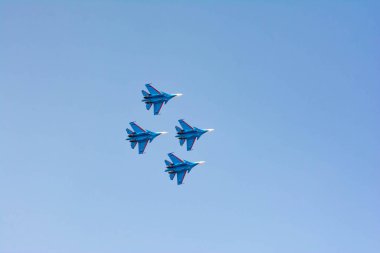 Pilotlar avcı uçaklarında yüksek akrobatik hareketler gösteriyor. Mavi gökyüzündeki uçak bombacıları. Gökyüzünde askeri uçak var.