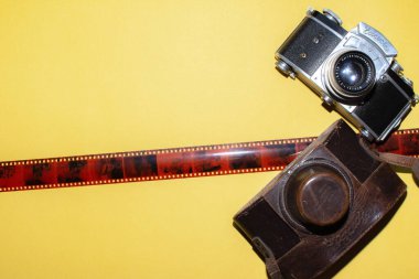 Camera, leather bag and tape for the picture. Yellow background and camera. Design for a photo studio