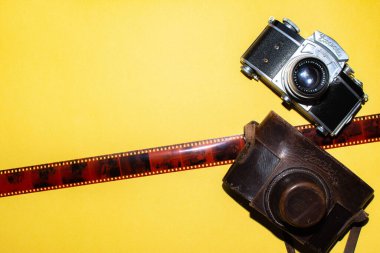 Camera, leather bag and tape for the picture. Yellow background and camera. Design for a photo studio