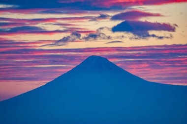 The top of the mountain is covered with clouds. Red clouds at the peak of the mountain during sunset. Beautiful sunset