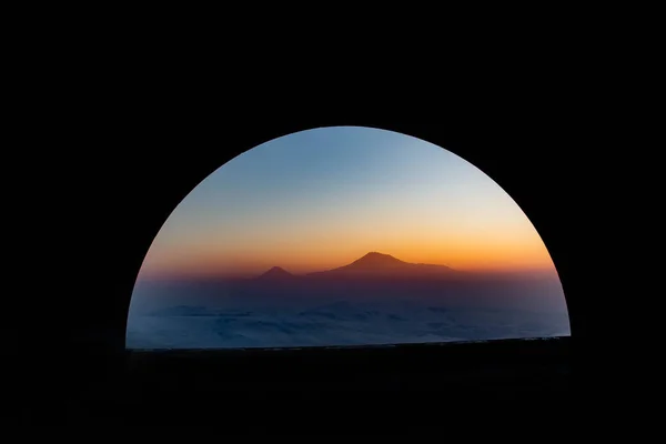 山とアーチ アーチを通して山と夕日が見える 太陽が山の上に沈む — ストック写真