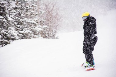 Snowboardcu dağdan iniyor. Çok şiddetli kar yağıyor.