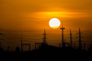 Güzel gündoğumu ve elektrik için metal kuleler. Büyük kızgın güneş ve turuncu gökyüzü