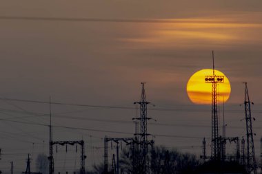 Güzel gündoğumu ve elektrik için metal kuleler. Büyük kızgın güneş ve turuncu gökyüzü