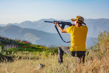 Silahlı bir avcı. Elinde silah tutan bir adam.