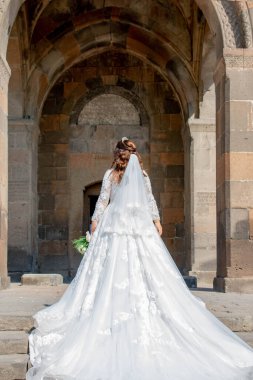 Bride in a white dress at the church. Wedding photo at the church. Bride and Church. Wedding bouquet in the hands of the bride