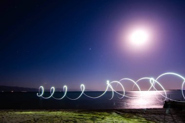Freezlight photos style. Beautiful night landscape - a tree on the seashore, golden sand of the sea and a bright glowing sky