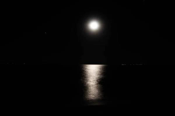 Reflection of the moon on the waters of the sea. Black waves of the sea and the moon