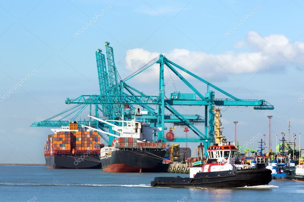 Huge container ship being unloaded with cranes in Antwerp container terminal - all recognizable logos and brands have been removed