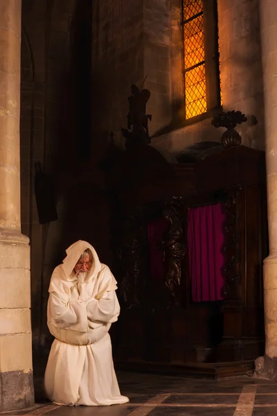 Kneeling monk in dark church — Stock Photo, Image