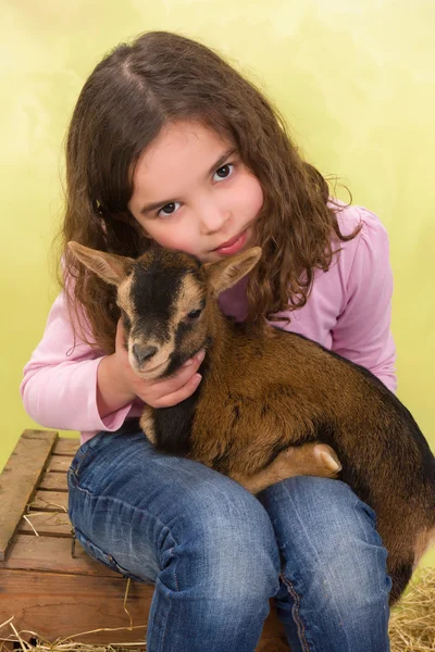 Girl hugging baby goat — Stock Photo, Image