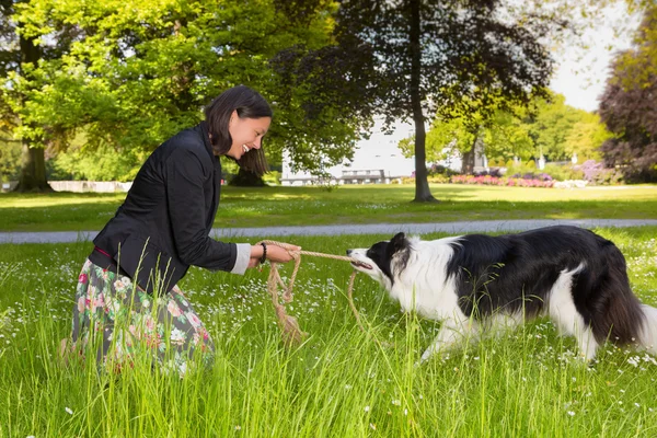 Rope pulling with her dog — Stock Photo, Image