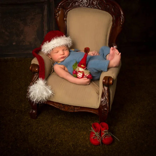 躺在老式扶手椅上睡在圣诞礼帽里的新生儿 — 图库照片