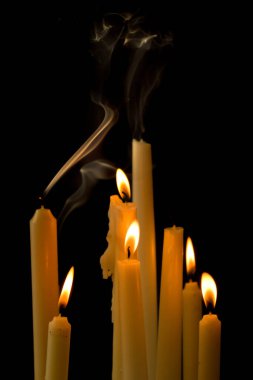 Siyah arka planda yanan beyaz kilise mumları.