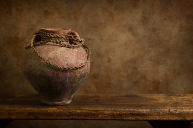 Still life of a rustic antique stoneware jug on a rustic old wooden shelf. 
