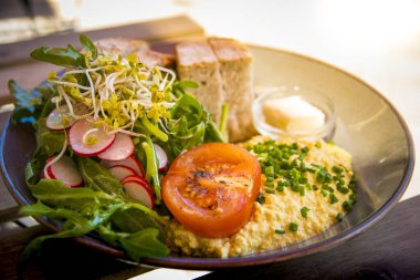 Sağlıklı vejetaryen kahvaltısı. Yumurta yerine domates, salata, turp, ekmek ve bitki bazlı tereyağı ile çırpılmış tofu.