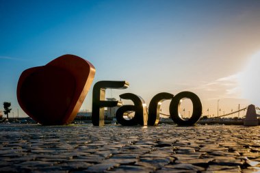 Faro, Portekiz, Eylül 2022: Şehrin limanındaki I Love Faro tabelasında gün batımı manzarası.