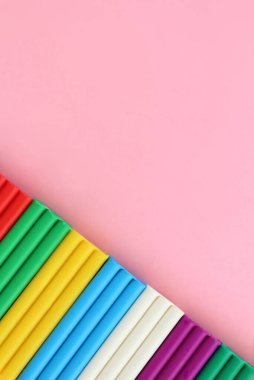 Renkli modelleme kil tuğlaları pembe yüzeyin köşesinde, fotokopi alanı ile çapraz olarak duruyordu. Dikey fotoğraf.