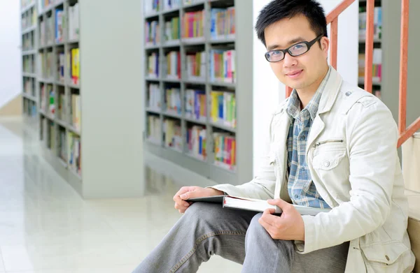 Pohledný muž sedí a čtení v knihovně — Stock fotografie