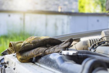 Arabanın kaputu altında çalışma eldiveni, hareket halindeki bir aracı tamir ederken güvenlik kurallarına uyma zorunluluğu