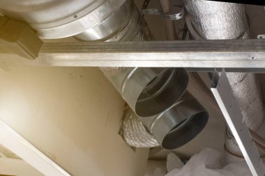 İşçiler tavanın altında havalandırma sistemi kuruyorlar. Ön ve arka plan bokeh etkisi ile bulanıklaşıyor.