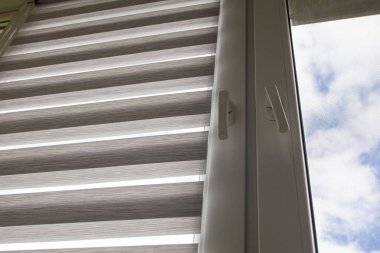 Mavi gökyüzüne karşı silindir kör ve sivrisinek ağlı plastik bir pencere