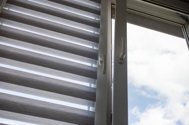 Mavi gökyüzüne karşı silindir kör ve sivrisinek ağlı plastik bir pencere