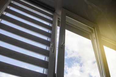 Mavi gökyüzüne karşı silindir kör ve sivrisinek ağlı plastik bir pencere