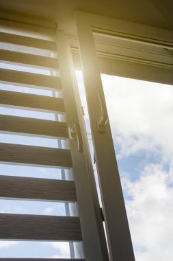 Mavi gökyüzüne karşı silindir kör ve sivrisinek ağlı plastik bir pencere