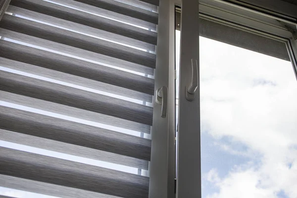 Mavi gökyüzüne karşı silindir kör ve sivrisinek ağlı plastik bir pencere