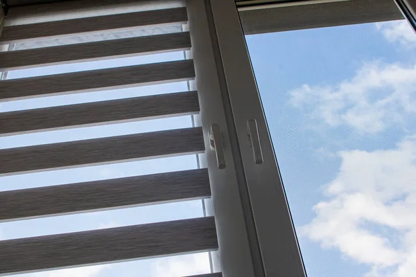 Mavi gökyüzüne karşı silindir kör ve sivrisinek ağlı plastik bir pencere