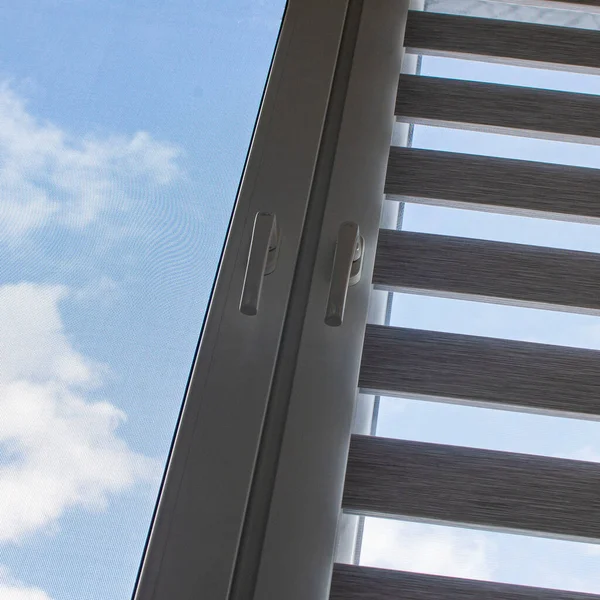 Mavi gökyüzüne karşı silindir kör ve sivrisinek ağlı plastik bir pencere