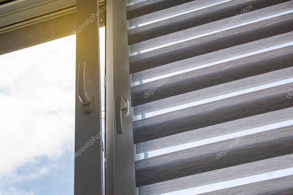 a plastic window with a roller blind and a mosquito net against a blue sky