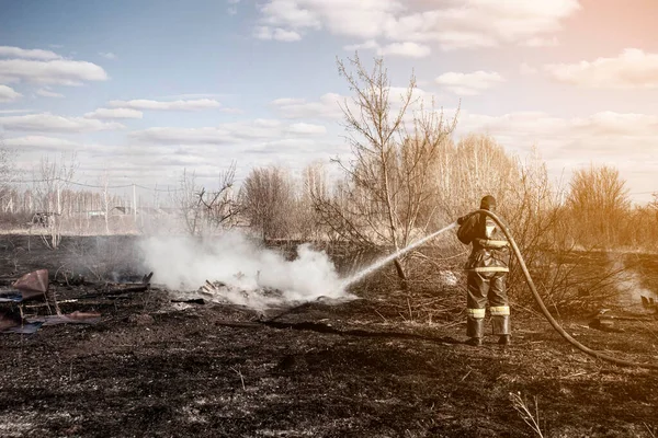 Ein Tapferer Feuerwehrmann Löscht Mit Hilfe Eines Wasserhydranten Einen Grasbrand — Stockfoto