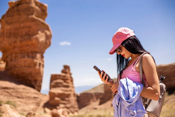 girl standing with a phone on the background of a blurred canyon