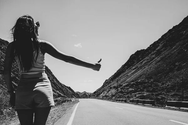 a young single woman of easy virtue, in light sexy clothes, voting on a highway in the desert, traveling alone