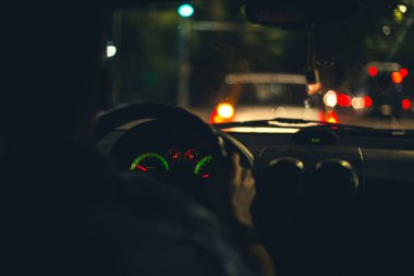 view from the passenger compartment of the night road illuminated by the fog lights of the car, with poor visibility on the wet road and dirty glass. Front and back background blurred with bokeh effect