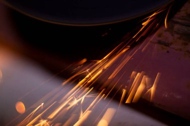 abstract image of sparks from a circular saw, photographed in close-up macro mode. Front and back background blurred with bokeh effect