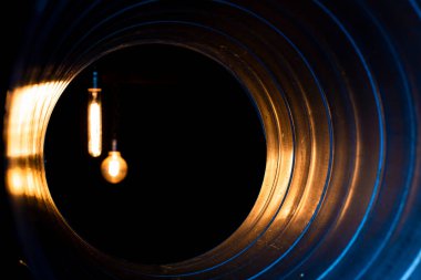 glowing bulbs with edison filament visible from the ventilation duct through the grate, the front and back background is blurred with bokeh effect