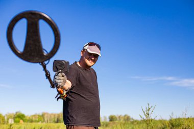 treasure hunter close-up with a metal detector, front and back background is blurred