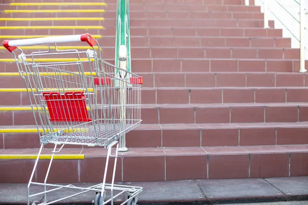 empty basket next to the stairs at the entrance to the supermarket, the background is blurred