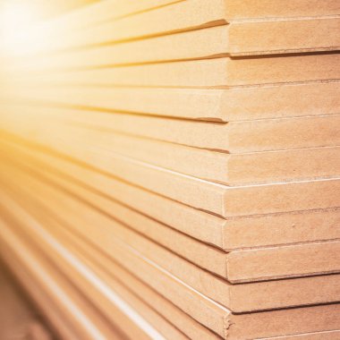 Bir dolap dükkanında düzgünce istiflenmiş bir yığın MDF paneli, arka plan bokeh efektiyle bulanıklaştırılmış