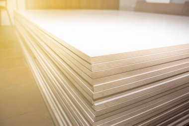 Bir dolap dükkanında düzgünce istiflenmiş bir yığın MDF paneli, arka plan bokeh efektiyle bulanıklaştırılmış