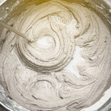 Çimento yapıştırıcıyı bir kovaya karıştırarak yakın plan, karışık havan topu dokusu.