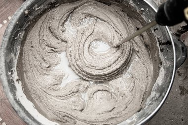 Çimento yapıştırıcıyı bir kovaya karıştırarak yakın plan, karışık havan topu dokusu.