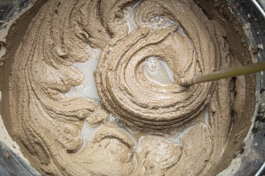 Çimento yapıştırıcıyı bir kovaya karıştırarak yakın plan, karışık havan topu dokusu.