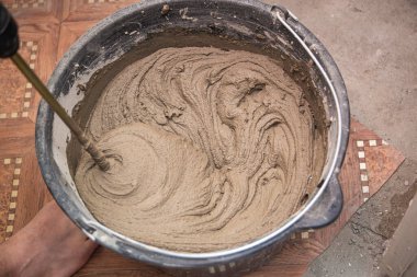 Çimento yapıştırıcıyı bir kovaya karıştırarak yakın plan, karışık havan topu dokusu.